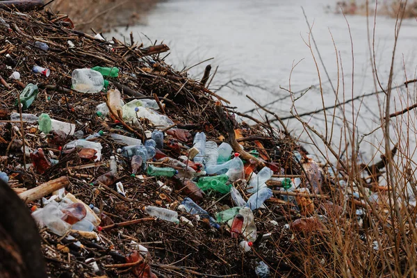 Plastic bottles near the river. Man pollutes the environment
