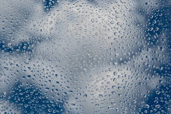 玻璃杯上的雨滴映衬着蓝云的天空 在天空的背景上滑落 — 图库照片