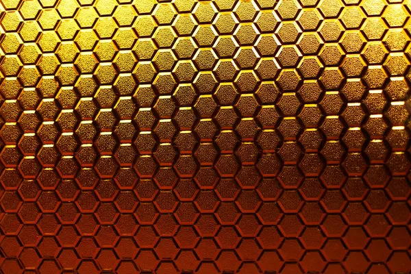 Stained glass texture with honeycomb pattern under sunlight. Gradient of gold and bronze colors of stained glass honeycombs