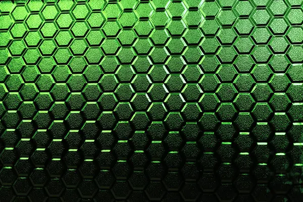Stained glass texture with honeycomb pattern under sunlight. Gradient of green colors of stained glass honeycombs