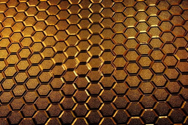 Stained glass texture with honeycomb pattern under sunlight. Gradient of gold and bronze colors of stained glass honeycombs
