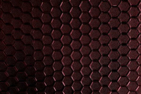 Stained glass texture with honeycomb pattern under sunlight. Gradient of carmine red colors of stained glass honeycombs