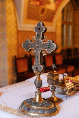 Tapınaktaki masada metal haç var. Kilisenin özellikleri sıcak tonlarda.