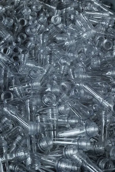 Close-up of PET preform blanks in a stack, used in plastic bottle manufacturing.