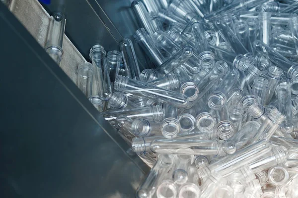 Close look at PET preforms, the initial stage of plastic bottle manufacturing on the conveyor.