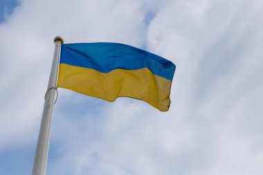 Dalgalı mavi gökyüzünün altında dalgalanan Ukrayna bayrağının gururunu ve güzelliğini yakala..