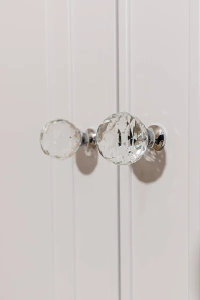 Delve into opulence with a detailed view of crystal knobs accentuating a white cabinet in a contemporary setting