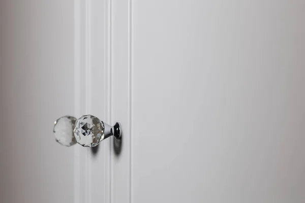 Embrace chic aesthetics with a close-up of crystal handles embellishing a stylish white cabinet in a modern interior