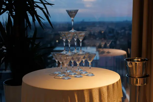 stock image A tower of empty champagne glasses stands on a table, waiting to be filled, with city view and greenery