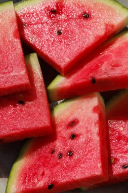 Taze kesilmiş üçgen karpuz dilimleri, tatlı ve ferahlatıcı bir yaz ikramı sunuyor.