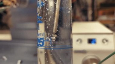 Kimya laboratuarındaki bir kimya laboratuvarında, organik çözücüden geçen nitrojen baloncuğu. Organik katmanlı karbondioksit kabarcığı. 4K bilimsel arkaplan kavramı.