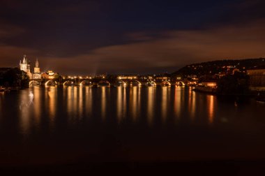 Charles Köprüsü Prag Kalesi ve Vltava Prag Nehri üzerindeki panoramik gece manzarası. Güneşin battığı, kırmızı tegıl çatıları ve broş kulesi olan eski şehir evlerinin manzarası..