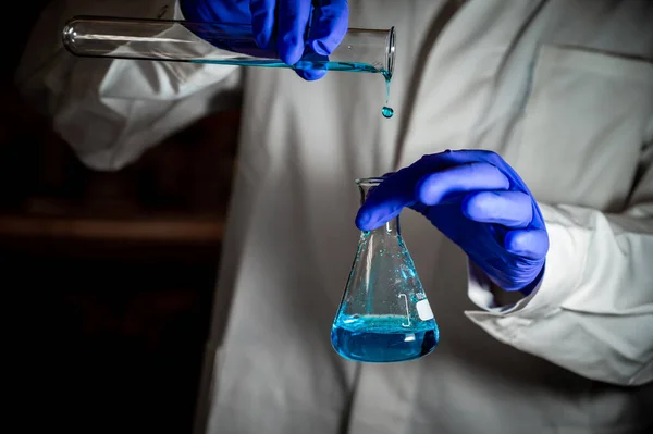 A woman scientist pouring Organic chemistry solution in a laboratory - radioactive - fluorescence. A copy space black background. Organic medicinal chemistry laboratory.