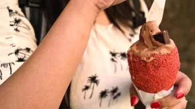 Beautiful woman is eating traditional Trdelnik or trdlo Czech sweet. Woman hand keep trdlo in Prague street. Street food. Trdelnik is a traditional sweet cake with sugar and cinnamon with Bread. 4K.
