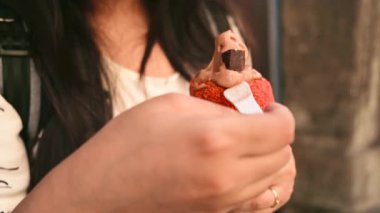 Beautiful woman is eating traditional Trdelnik or trdlo Czech sweet. Woman hand keep trdlo in Prague street. Street food. Trdelnik is a traditional sweet cake with sugar and cinnamon with Bread. 4K.