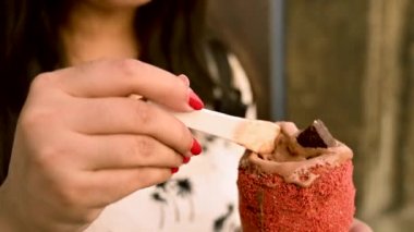 Beautiful woman is eating traditional Trdelnik or trdlo Czech sweet. Woman hand keep trdlo in Prague street. Street food. Trdelnik is a traditional sweet cake with sugar and cinnamon with Bread. 4K.