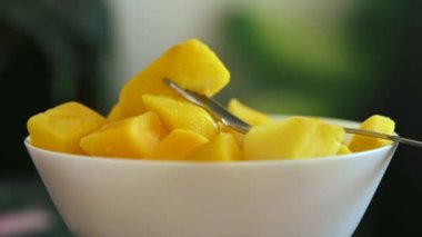 Tropikal mango küplerini taze meyve dolu beyaz bir kasede ve koyu arkaplanda fotokopi alanı olan nane şekeriyle tazeliyorum..