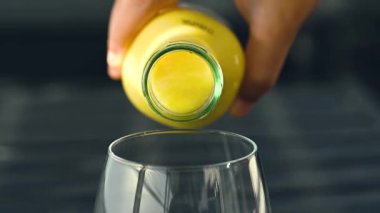 Koyu arkaplanda taze meyve, nane ve saman bulunan cam bir şişedeki tropikal mango lassi smoothie 'yi yavaş çekimde kopyalama alanı ile tazeliyorum..