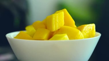 Tropikal mango küplerini taze meyve dolu beyaz bir kasede ve koyu arkaplanda fotokopi alanı olan nane şekeriyle tazeliyorum..