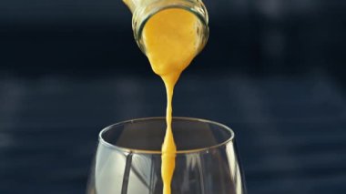 Koyu arkaplanda taze meyve, nane ve saman bulunan cam bir şişedeki tropikal mango lassi smoothie 'yi yavaş çekimde kopyalama alanı ile tazeliyorum..