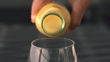 Koyu arkaplanda taze meyve, nane ve saman bulunan cam bir şişedeki tropikal mango lassi smoothie 'yi yavaş çekimde kopyalama alanı ile tazeliyorum..