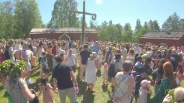 Umea, İsveç - 24 Haziran 2022 İsveç Renkli çiçek tacıyla ve 4K ile İsveç 'in ortasındaki yaz gününün tadını çıkaran insanlar. Yaz ortası kutlaması.