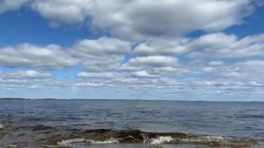 Denizin üzerinde güzel bir bulut manzarası, günbatımının hızlandırılmış çekimi. Plaj denizinin ve bulutların güzel bir hava gününde mavi gökyüzünde hareket etmesinin zamanına uygun doğa manzarası. 4K bulut takibi.