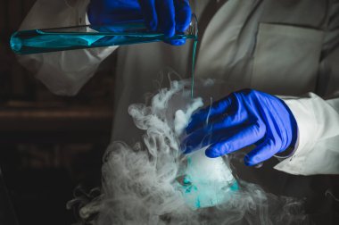 Bir laboratuarda organik reaksiyon gösteren bir kadın bilim adamı. Duman, radyoaktif, florasan. Bir fotokopi alanı siyah arka planı. Organik tıbbi kimya laboratuvarı.