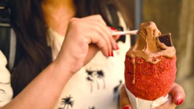 Turist kadın geleneksel Trdelnik ya da trdlo Çek tatlısını deniyor. Prag caddesinde Trdlo 'yu tutan kadın. Sokak yemeği. Trdelnik şekerli ve tarçınlı geleneksel tatlı bir pasta. 4K.