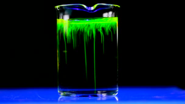 女性科学者がグリーン蛍光ソリューションを用いて ヘルスケア薬物開発のためのダークバイオ医薬品化学研究所のガラスコニカルフラスコで実験しました 4Kコピースペース — ストック動画