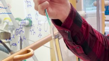 Biyoteknoloji araştırma ve uyuşturucu geliştirme laboratuvarında temiz NMR tüplerinde reaksiyon karışımından örnekler hazırlayan bir araştırmacı bilim adamı