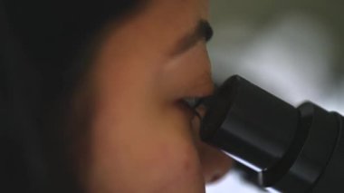 Mikroskop altında örneklere bakan kadın bir bilim adamının gözlerini kapat. Modern Laboratuvarda Teknolojik Ekipmanlarla çalışan 4K Mikrobiyolog. Biyokimya, ilaç..