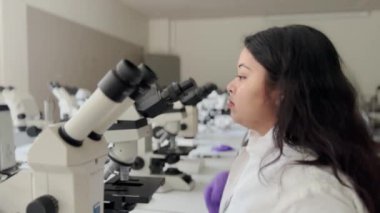 Biyomedikal Bilimler Laboratuvarı: Örnek almak için Mikroskop Altında Bakan Güzel Bilim Adamlarının Portresi. Genç bilim adamı bir laboratuarda mikroskoba bakıyor..