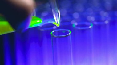 Bilim adamının test tüpüne damlayan reaksiyonu 4K yavaş çekimde. Kadın bilim adamı kimyasalları kullanarak bir laboratuvar ya da hastanede hastalıkları araştırıp tedavi ediyor. Tıbbi tedavi kavramları.