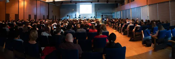 People attending to an European scientific conference. A huge gathering of people meeting for scientific discussion.