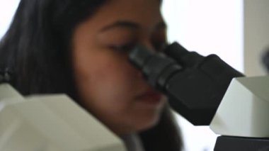 Kadın araştırmacı bilim adamı mikroskop altında örneklere bakıyor. Modern Laboratuvarda Teknolojik Ekipmanlarla çalışan 4K Mikrobiyolog. Biyokimya, ilaç..