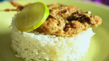 Tahta bir masada sarı bir tabakta servis edilen balık, pirinç ve limon dilimleri ile süslenmiş güzel bir yemek tabağı. Öğle ve akşam yemeği için Hint yemeği..