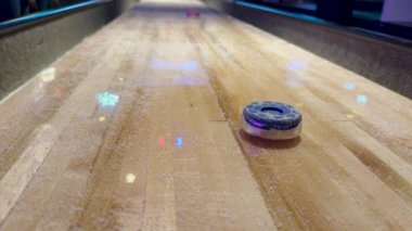 Shuffleboard Masası 'nın Ağırlıklarının Yakın Çekimi. Yavaş çekimde masa hokeyi diski numaralara kayıyor. Kağıt disk peynirle kaplı tahtada kayıyor.