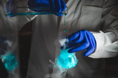 Mavi renk çözeltisiyle dumanlı deneyler. Kimyasal reaksiyon üzerinde çalışan bilim adamı cam şişeden yoğun duman çıkarıyor. Kopyalama alanı