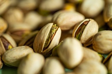 Fıstıklı fındık. Yığınla fıstık var. Yeşil arka planda izole edilmiş sağlıklı organik fındık. Kopyalama alanı