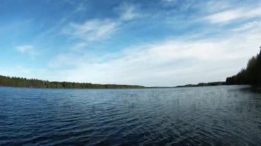 Gölün üzerindeki bulutlu manzara, günbatımında hareketli çekim. Plaj denizinin ve bulutların güzel bir hava gününde mavi gökyüzünde hareket etmesinin zamanına uygun doğa manzarası. 4K bulut takibi.