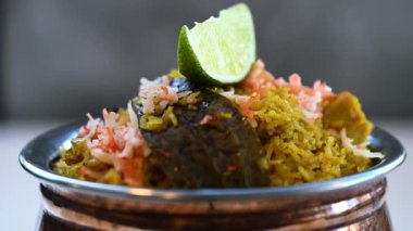 Güzel dekore edilmiş biryani ve pirinç kasesinde servis edilen limon dilimleriyle kızartılmış pirinç. Öğle ve akşam yemeği için Hint yemeği..