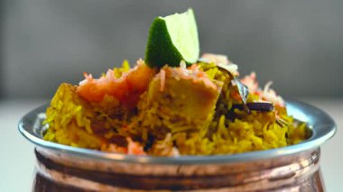 Güzel dekore edilmiş biryani ve pirinç kasesinde servis edilen limon dilimleriyle kızartılmış pirinç. Öğle ve akşam yemeği için Hint yemeği..