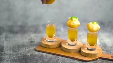 Baharatlı suyla kaplı bir bardakta Hint sokak yemeği fuşkası yakın. Pani puri Hindistan 'da bir sohbet konusu. 4K Hint sokak yemekleri.