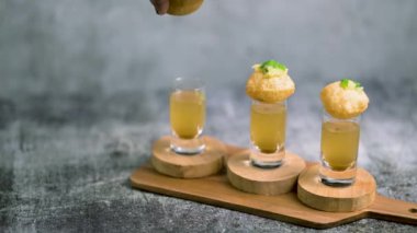 Baharatlı suyla kaplı bir bardakta Hint sokak yemeği fuşkası yakın. Pani puri Hindistan 'da bir sohbet konusu. 4K Hint sokak yemekleri.