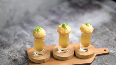 Baharatlı suyla kaplı bir bardakta Hint sokak yemeği fuşkası yakın. Pani puri Hindistan 'da bir sohbet konusu. 4K Hint sokak yemekleri.