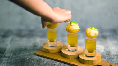 Baharatlı suyla kaplı bir bardakta Hint sokak yemeği fuşkası yakın. Pani puri Hindistan 'da bir sohbet konusu. 4K Hint sokak yemekleri.