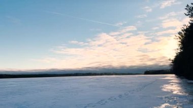 Donmuş karla kaplı bir göl ve gün batımının kış manzarası. Noel kışı güzel manzara, sinematik 4K güzel sakin doğa videosu..