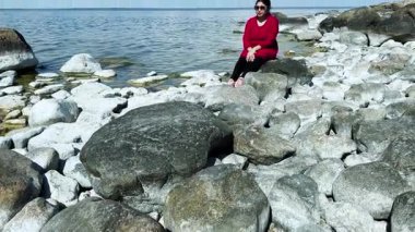 Deniz kıyısında dinlenen Asyalı bir kadın. Huzur anlarında bulunan ruh sağlığı ve kendine güvenin ilham kaynağı. Kadınlar boş vakitlerini doğada geçirirler.. 