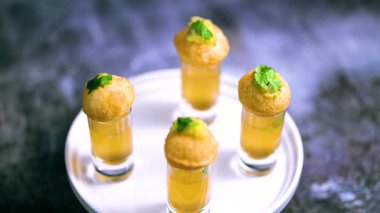 Baharatlı suyla kaplı bir bardakta Hint sokak yemeği fuşkası yakın. Pani puri Hindistan 'da bir sohbet konusu. 4K Hint sokak yemekleri.